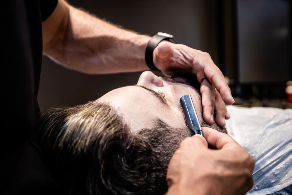 Barbero afeitando con navaja a un cliente en el interior de Zarevila